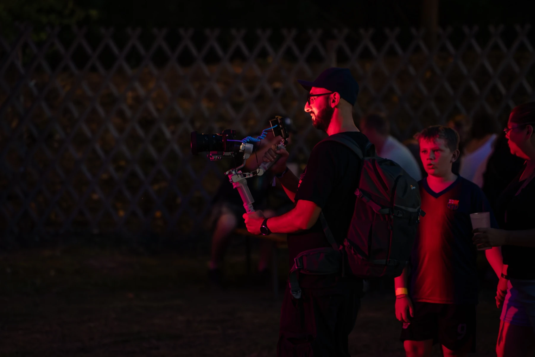 Event-Videograf Arsen Stepanian mit Gimbal im Einsatz bei einer kulturellen Veranstaltung mit atmosphärischer roter Beleuchtung.