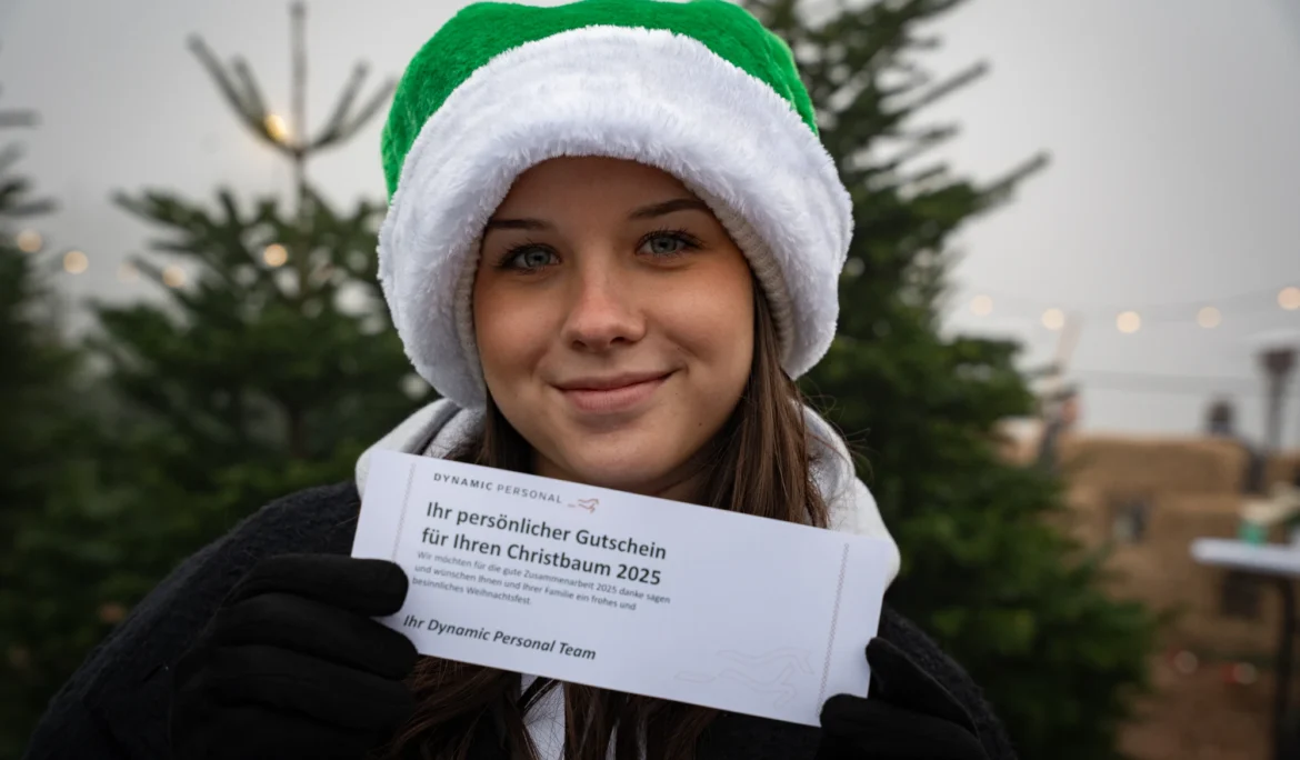 Sympathisches Mitarbeiter-Portrait mit Weihnachtsmütze und Gutschein – fröhliche Eventdokumentation der Dynamic Personal Weihnachtsfeier.