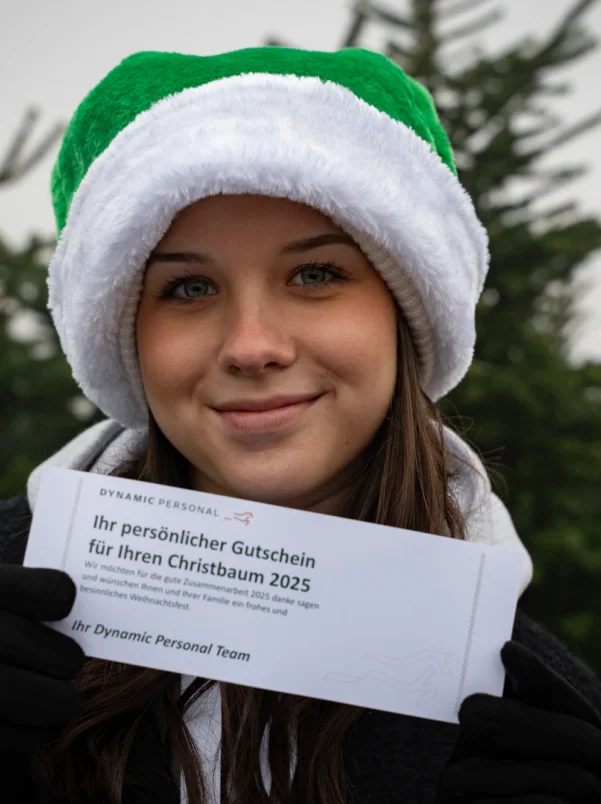 Sympathisches Mitarbeiter-Portrait mit Weihnachtsmütze und Gutschein – fröhliche Eventdokumentation der Dynamic Personal Weihnachtsfeier.