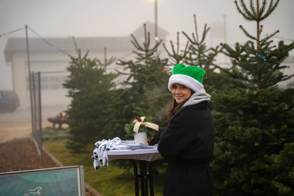 Authentische Eventfotografie im Christbaumservice Traiskirchen: Ein Gast mit grüner Weihnachtsmütze auf der Outdoor-Weihnachtsfeier von Dynamic Personal.