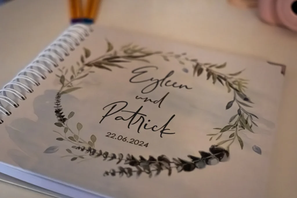 Detailaufnahme des Hochzeits-Gästebuchs: Liebevoll gestaltetes Buch mit floralem Design für die persönlichen Glückwünsche der Gäste bei der Feier.