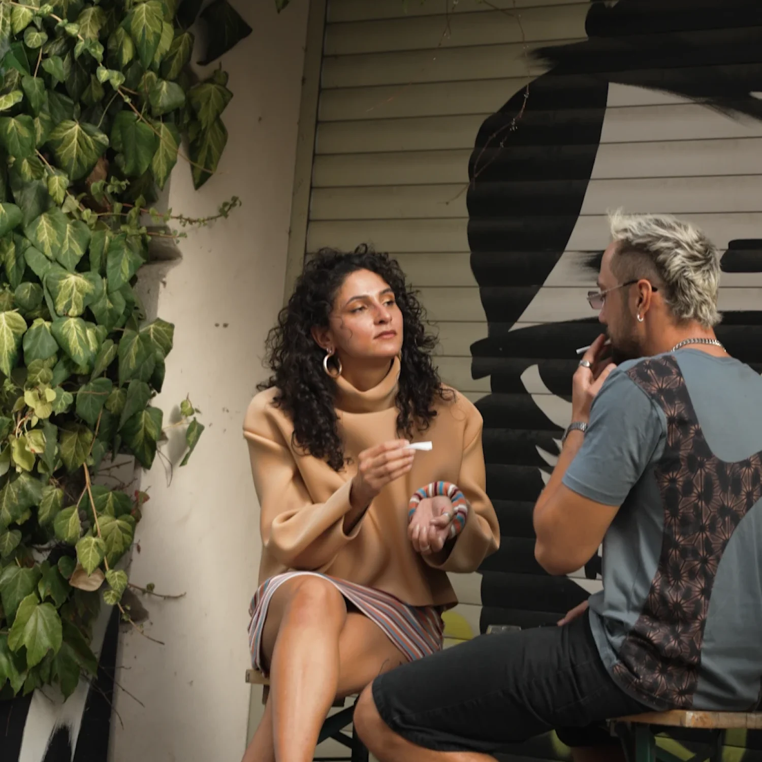 Lifestyle Szene der Fashion Kampagne: Model und Begleiter sitzen im Außenbereich einer urbanen Location in Wien