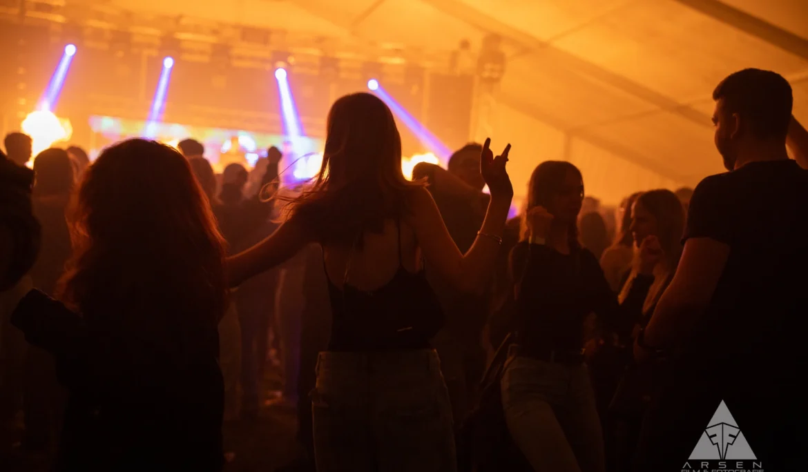 Atmosphärische Eventfotografie beim Greenfield 2025: Tanzende Menge in warmem Bühnenlicht in Kleinhadersdorf