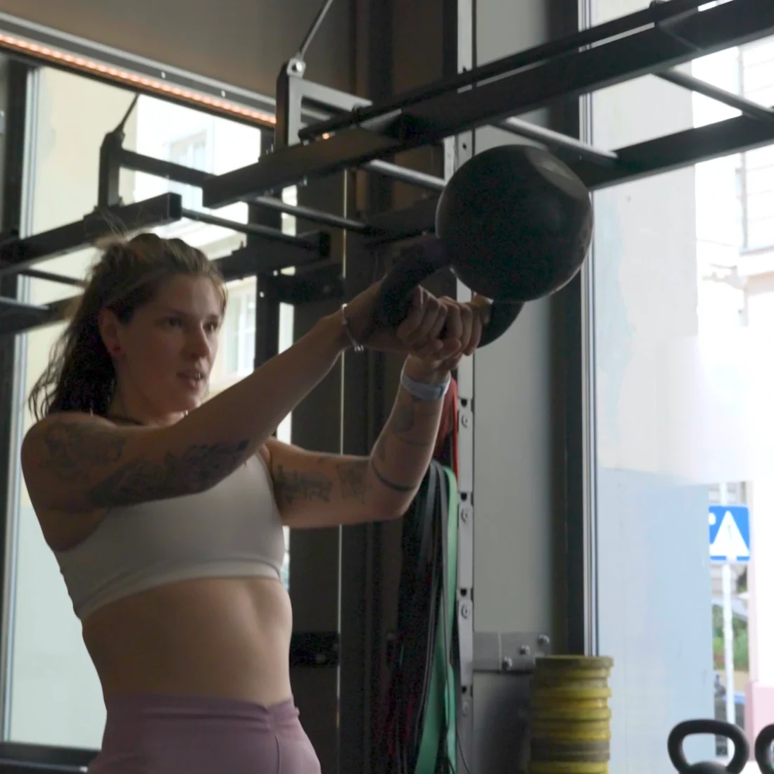 Fitness Coach Ines Gruber bei der Ausführung von Kettlebell Swings vor einem hellen Fenster