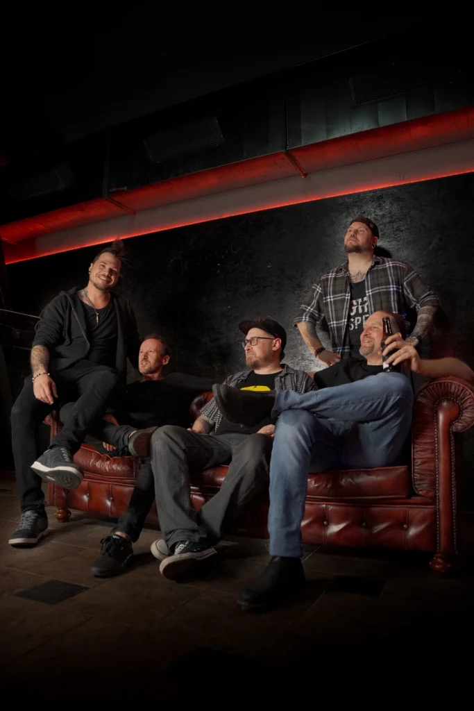 Kreatives Band-Gruppenfoto auf einem Ledersofa: Inszeniertes Bandshooting der RainbowKissers in der Location B10 Hagenberg.