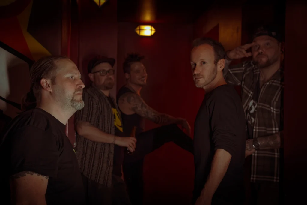 Atmosphärisches Bandfoto der RainbowKissers im Studio-Setting mit warmer, roter Beleuchtung.