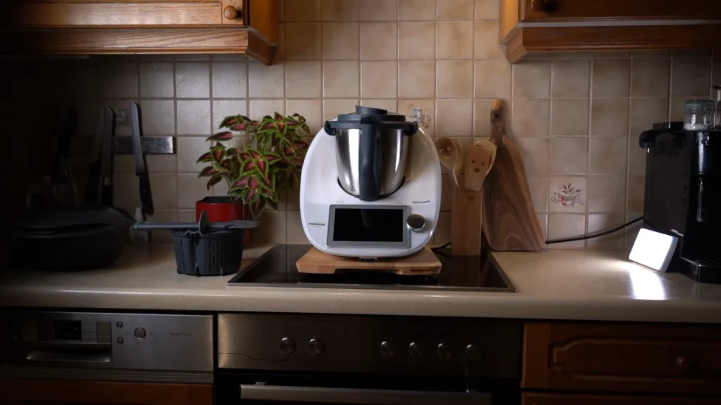 Atmosphärisches Set-Design für den Videodreh: Der Thermomix TM6 steht auf einem Holzbrett in einer authentischen Küche mit gefliestem Hintergrund und Dekoration.