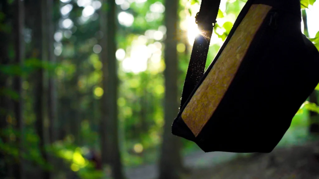 Nahaufnahme der Textur eines bandha Upcycling-Rucksacks vor einem sonnendurchfluteten Waldhintergrund