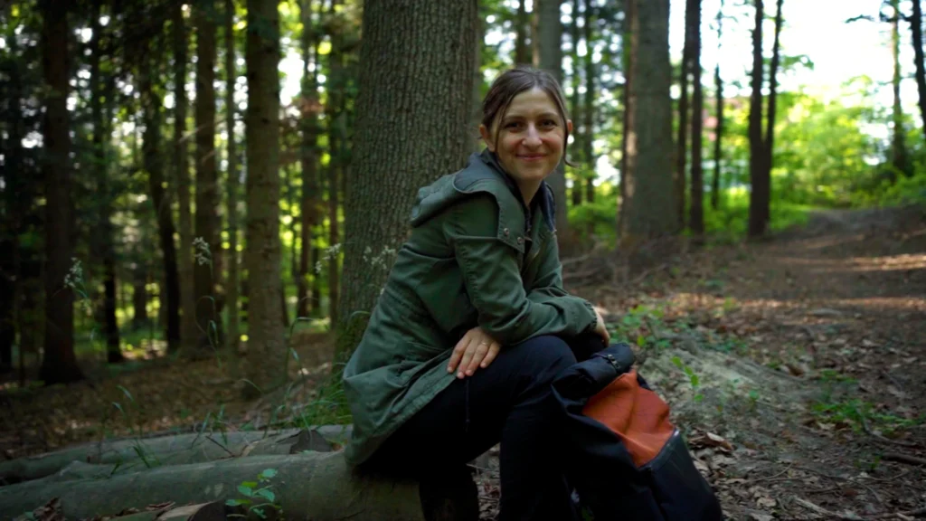 Gründerin Daniela Unger von bandha e.U. sitzt mit einem Upcycling-Rucksack im Wienerwald bei Altlengbach