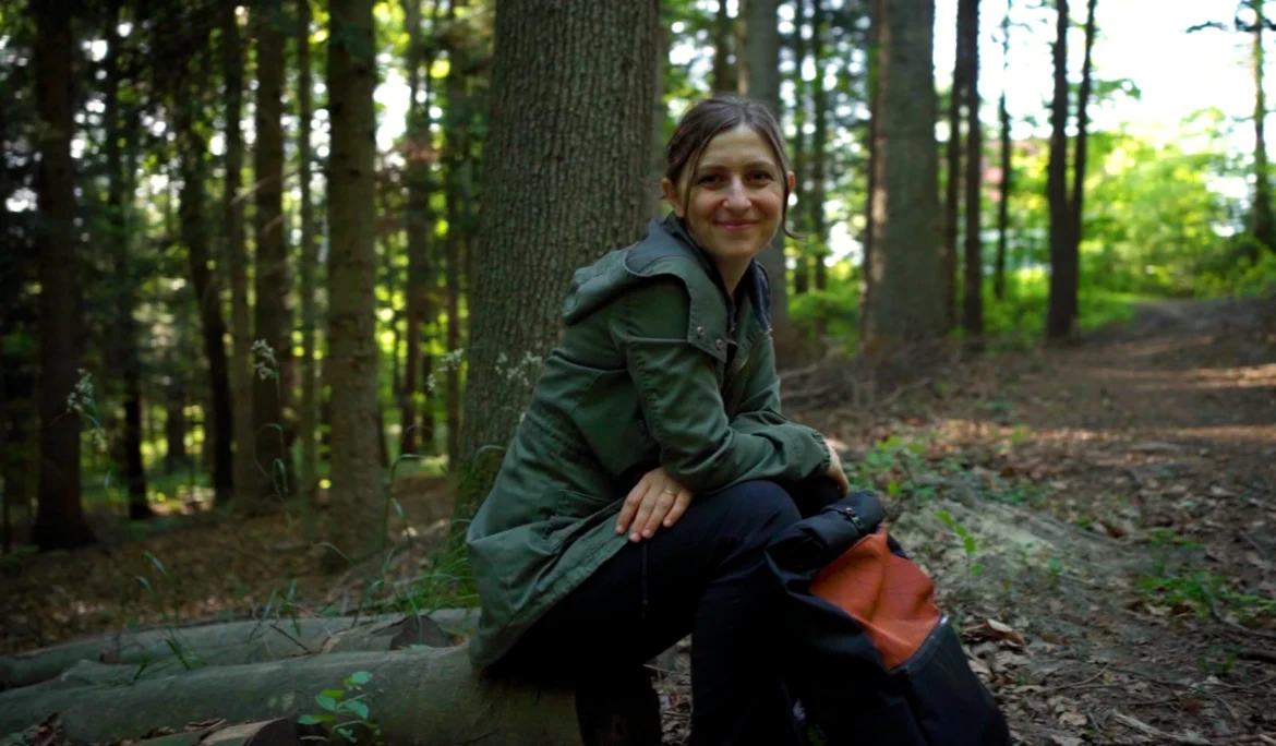 Gründerin Daniela Unger von bandha e.U. sitzt mit einem Upcycling-Rucksack im Wienerwald bei Altlengbach