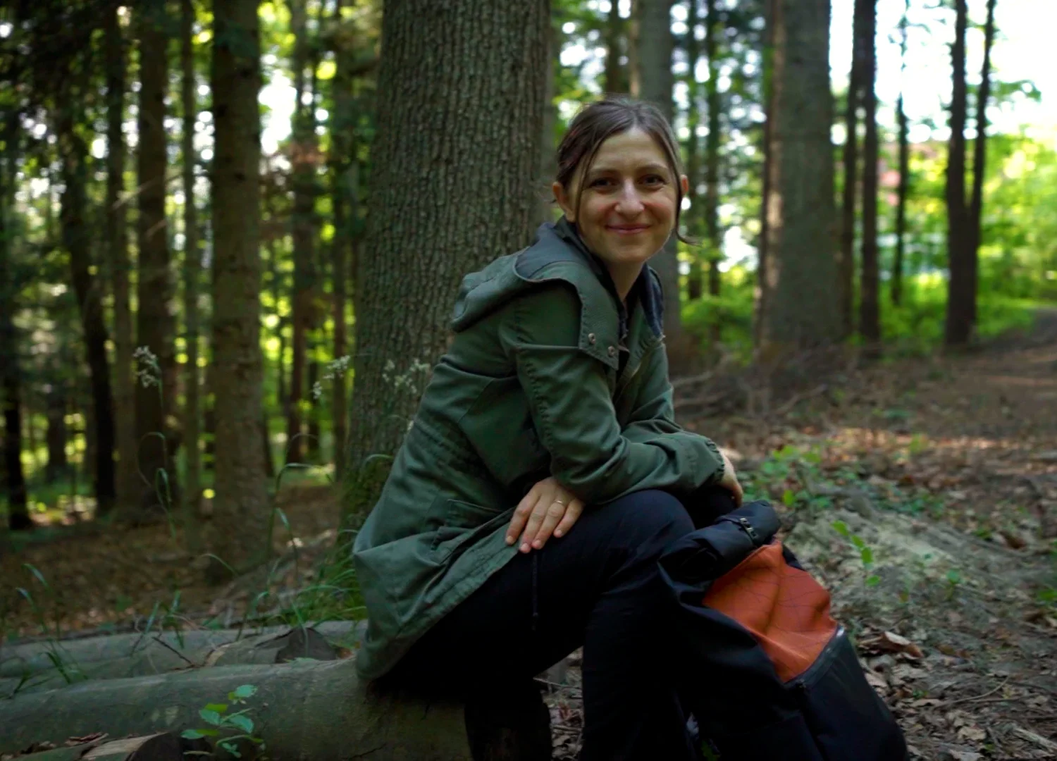 Gründerin Daniela Unger von bandha e.U. sitzt mit einem Upcycling-Rucksack im Wienerwald bei Altlengbach