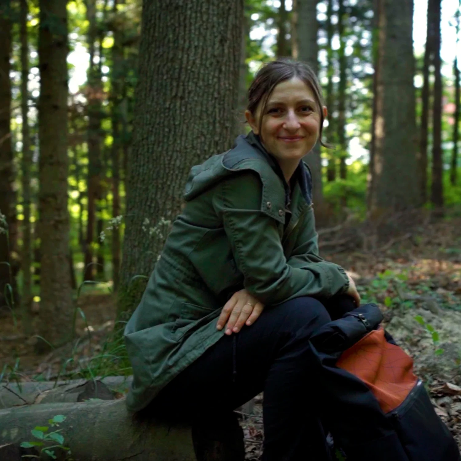 Gründerin Daniela Unger von bandha e.U. sitzt mit einem Upcycling-Rucksack im Wienerwald bei Altlengbach