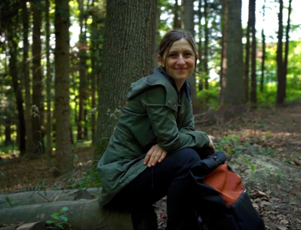 Gründerin Daniela Unger von bandha e.U. sitzt mit einem Upcycling-Rucksack im Wienerwald bei Altlengbach