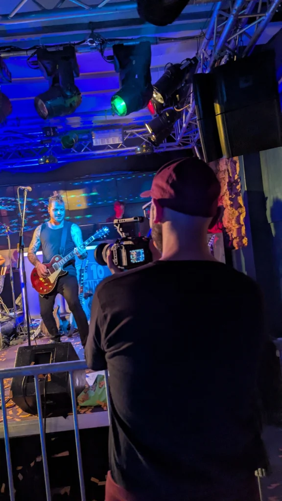 Professionelle Event-Videografie: ArsMotion Videograf filmt einen Gitarristen live auf der Bühne – Blick hinter die Kulissen einer Konzert-Produktion.