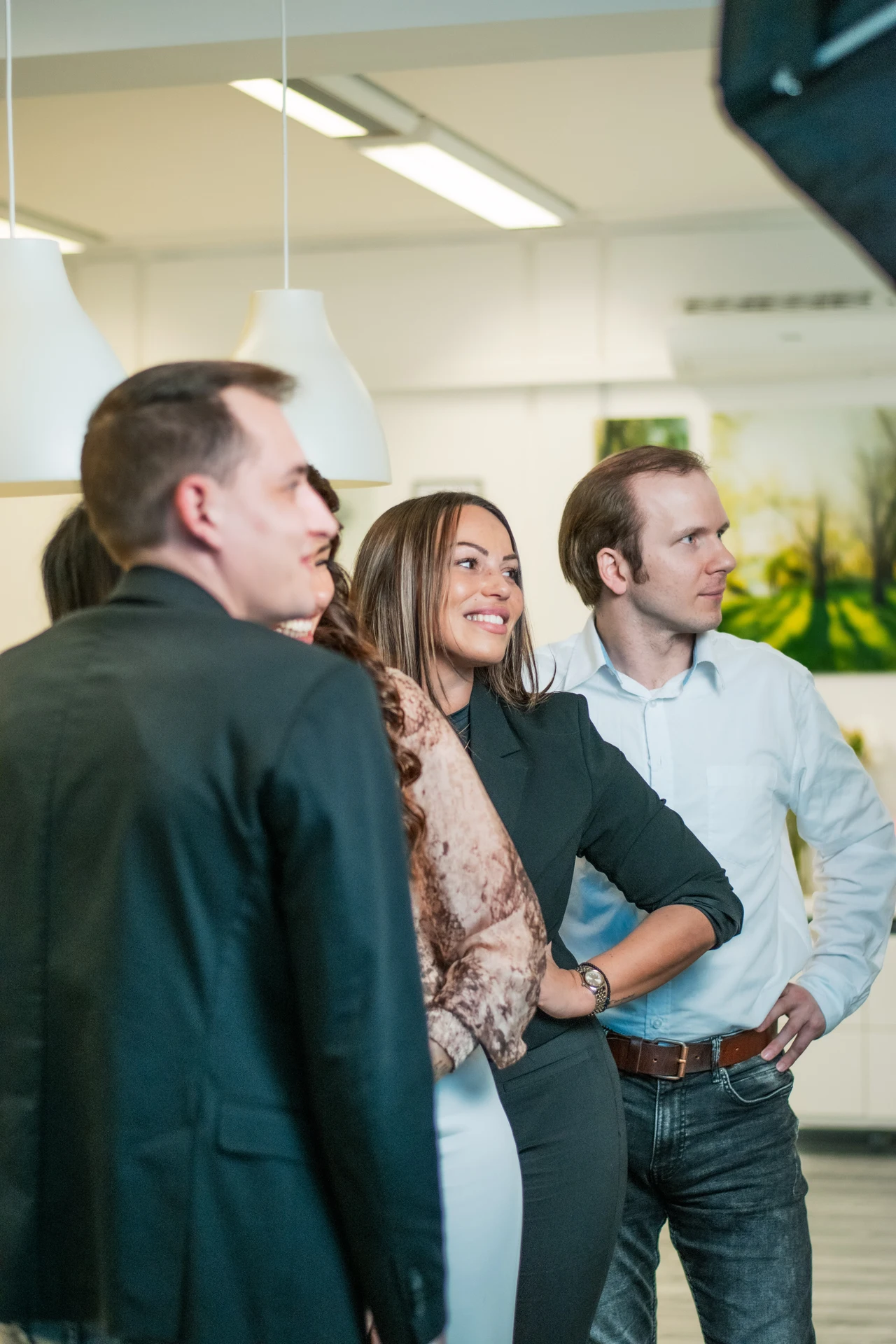 Vier Mitarbeiter von Dynamic Personal stehen im Büro zusammen und blicken lächelnd in Richtung der Kameraausrüstung.