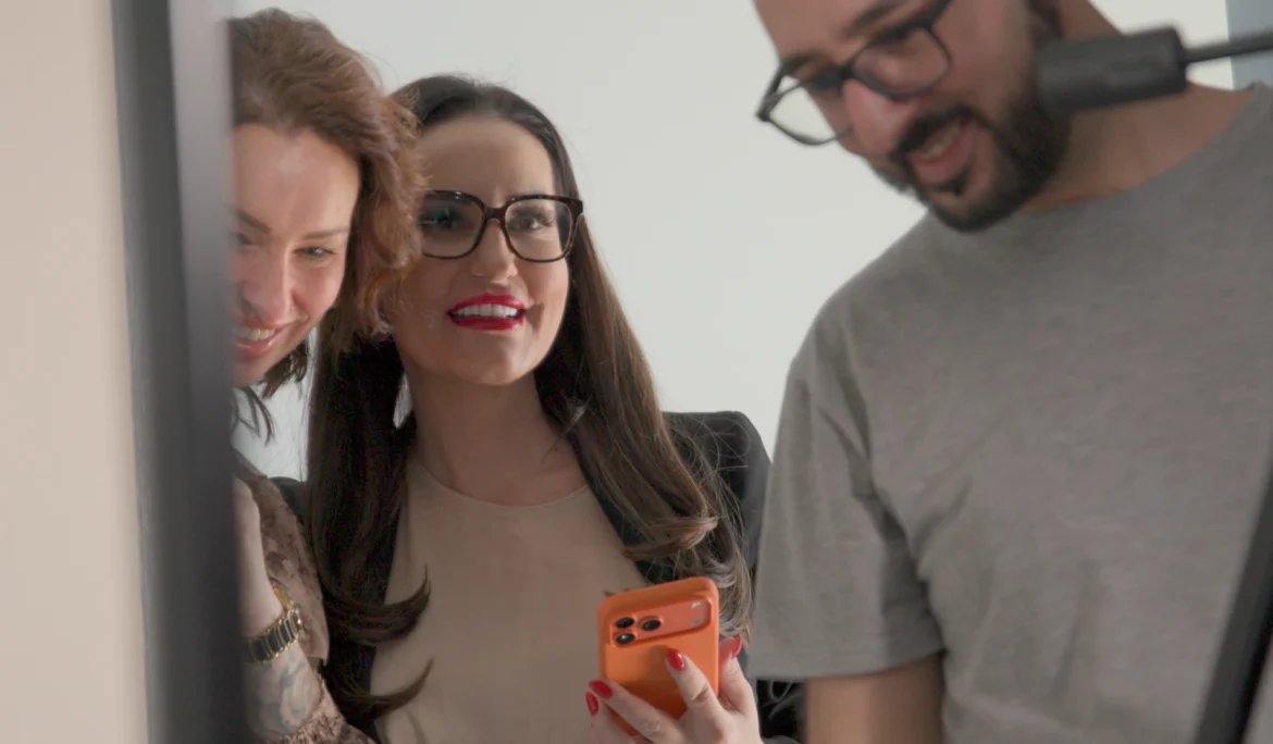 Mediengestalter Arsen Stepanian und Dijana von Dynamic Personal sichten gemeinsam gut gelaunt die ersten Ergebnisse des Videodrehs auf einem Smartphone.